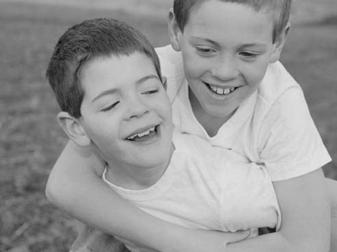 Black and white photo of two brothers, one giving the other a piggyback ride