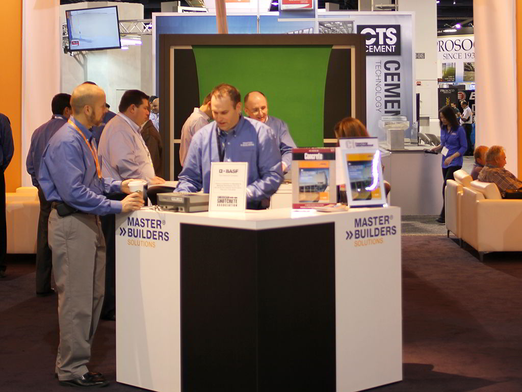 Event tech presenting Master Builders product in the booth, with guests having their photos taken in the background