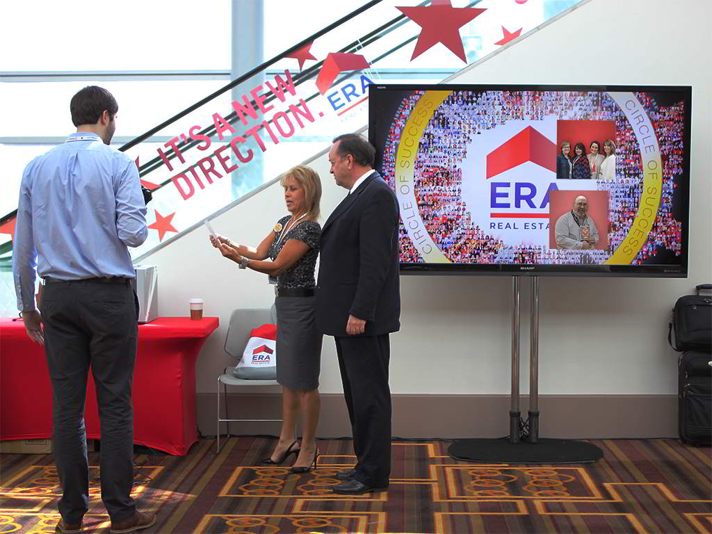 Guests viewing their printed mosaic photo takeaways at the ERA Realty event
