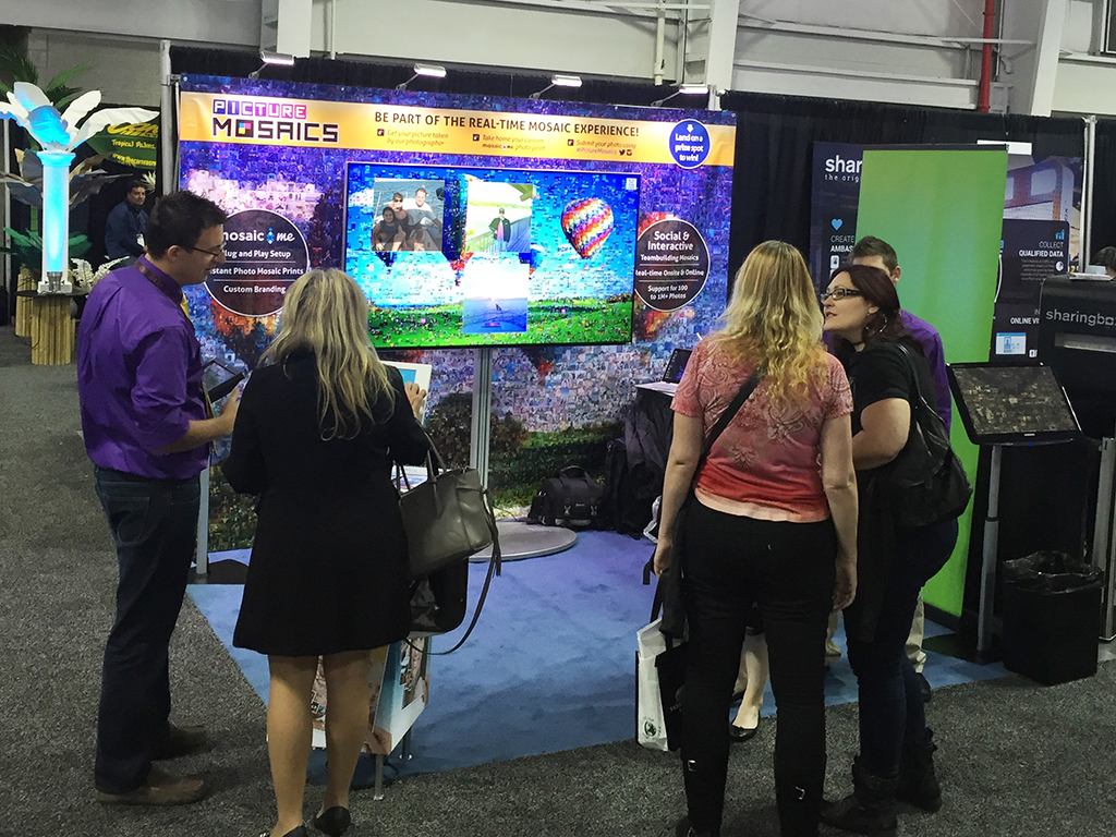 Group viewing the digital mosaic while a participant uses the MosaicMe kiosk