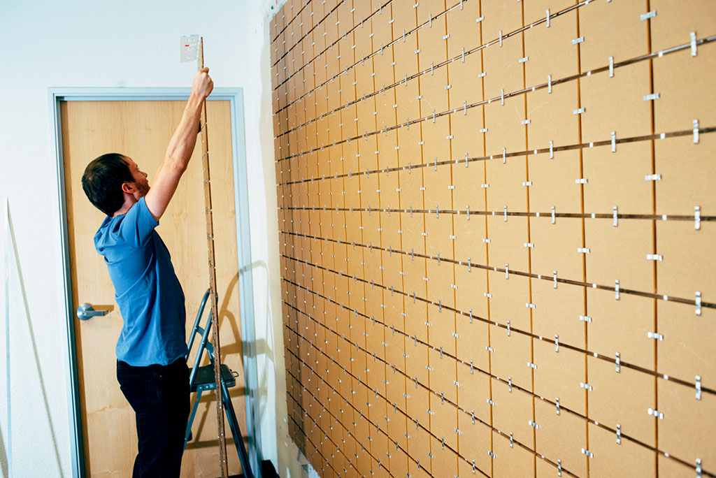 Person preparing the wall for a photo mosaic installation