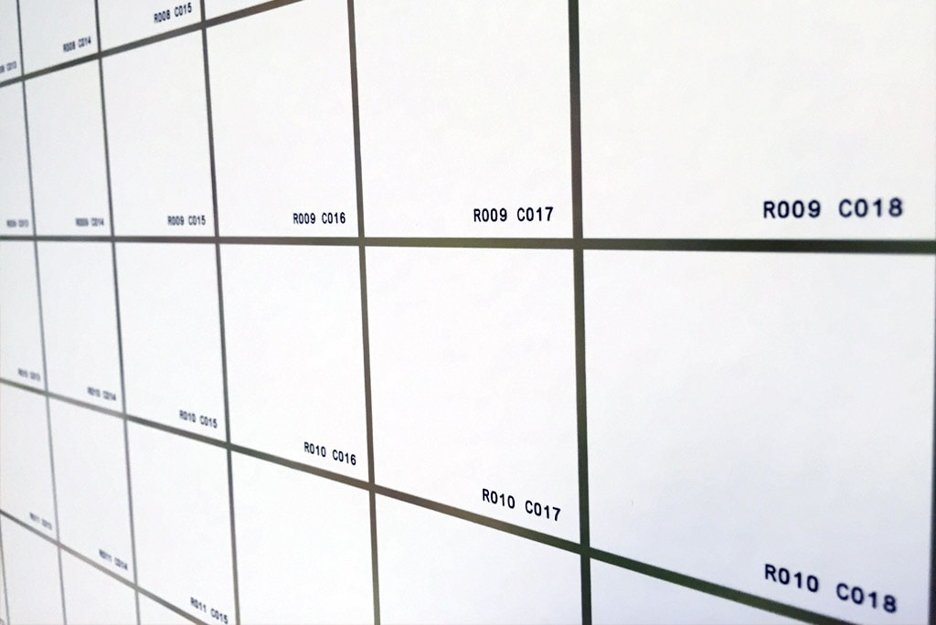 Close-up of mosaic photo tiles with printed grid coordinates for placement