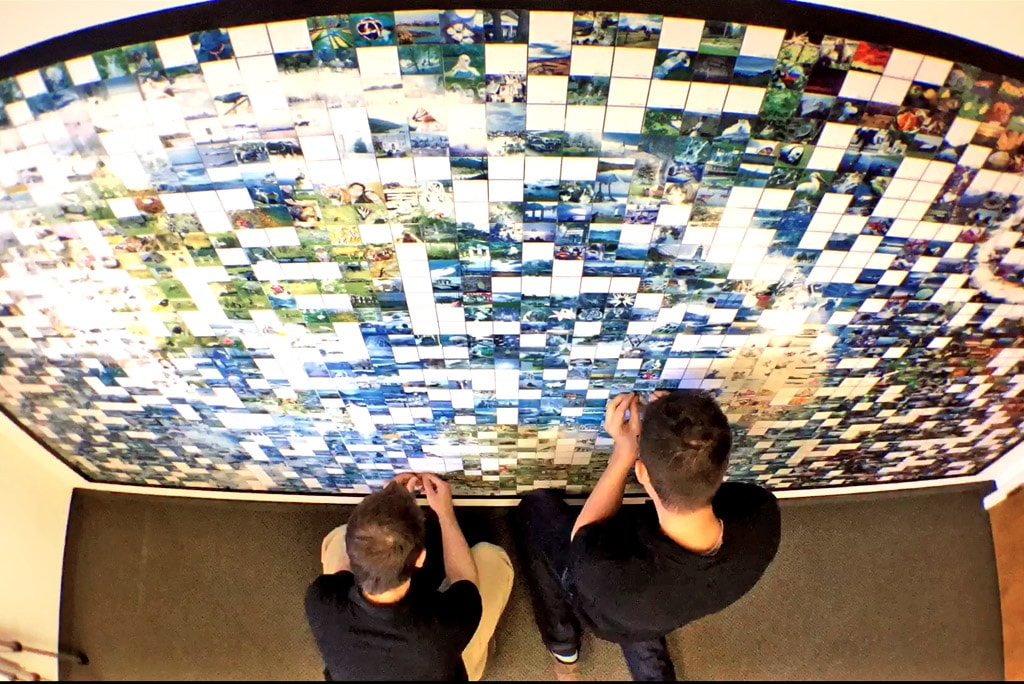 Overhead shot of two participants adding their tiles to the photo mosaic