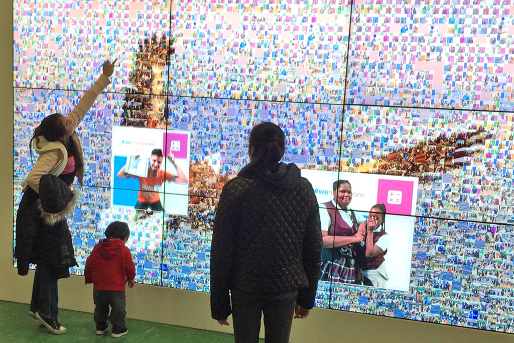 Family viewing the digital mosaic display with popping photo animation
