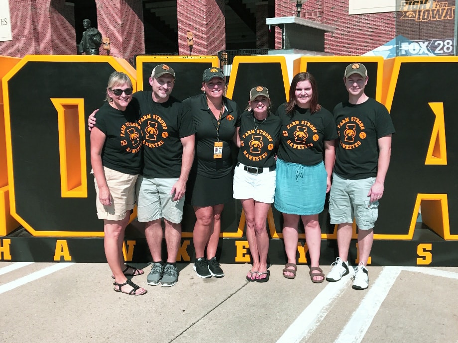 Group of Iowa Hawkeye fans posing in front of an Iowa sign at the event