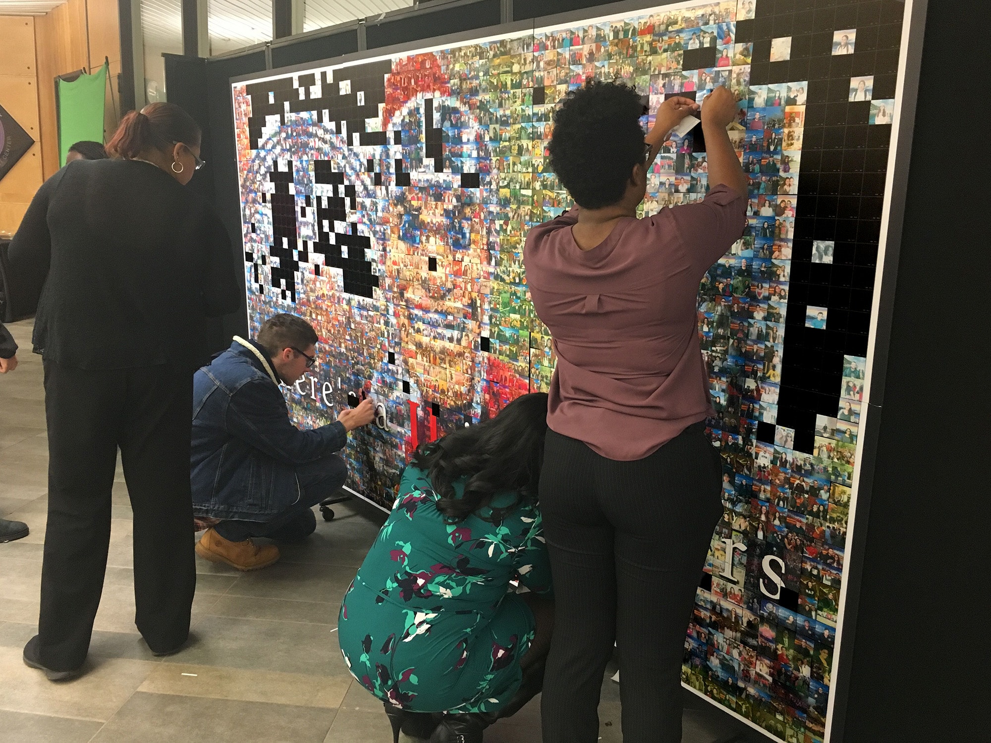 Students adding their photo tiles to the There’s a U in Rutgers mosaic wall