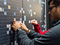 Student placing their printed photo tile onto the Rutgers mosaic wall