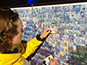 Guest placing their printed photo tile onto the Delaware First mosaic wall