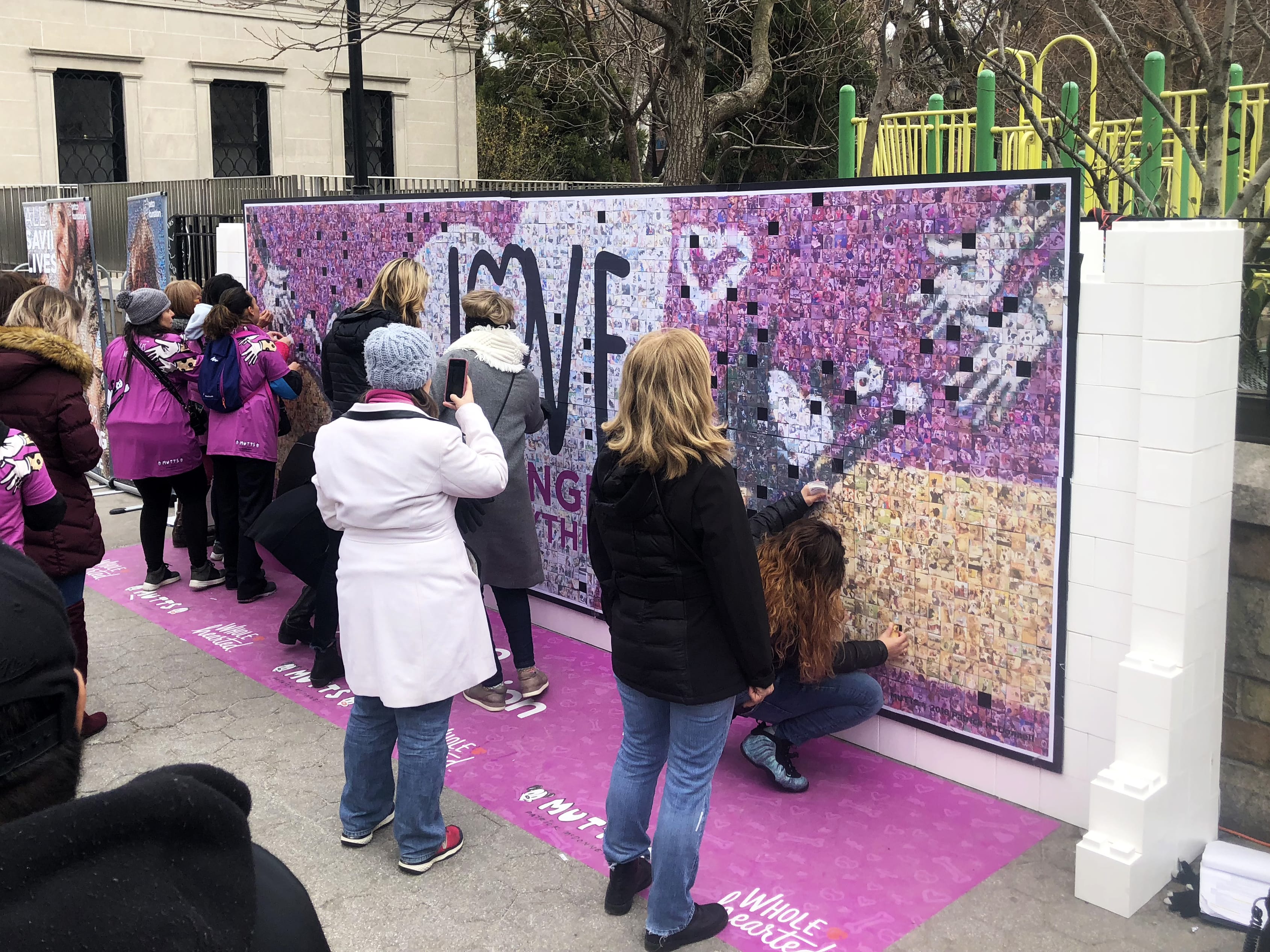 Crowd engaging with the mosaic wall—placing tiles, taking photos, and viewing progress