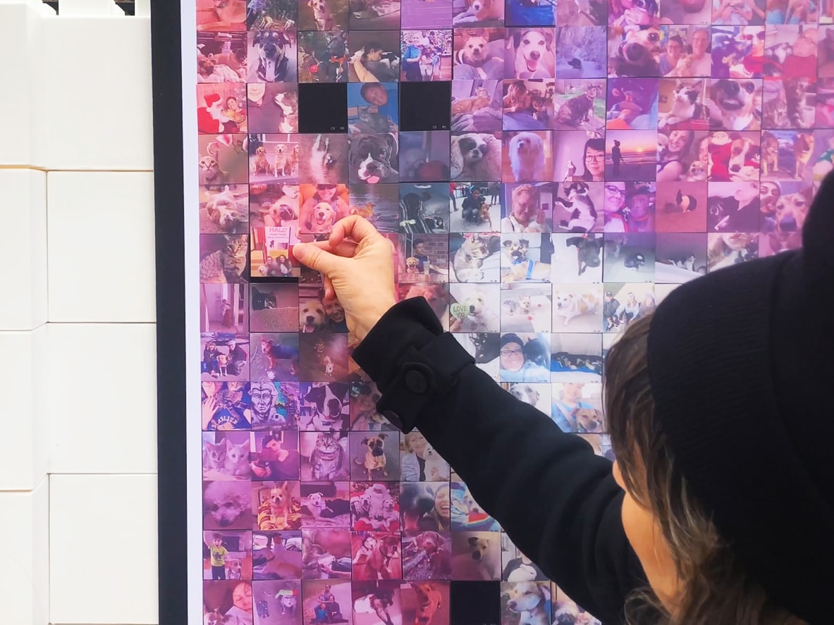Guest placing their printed photo tile onto the collaborative mosaic wall