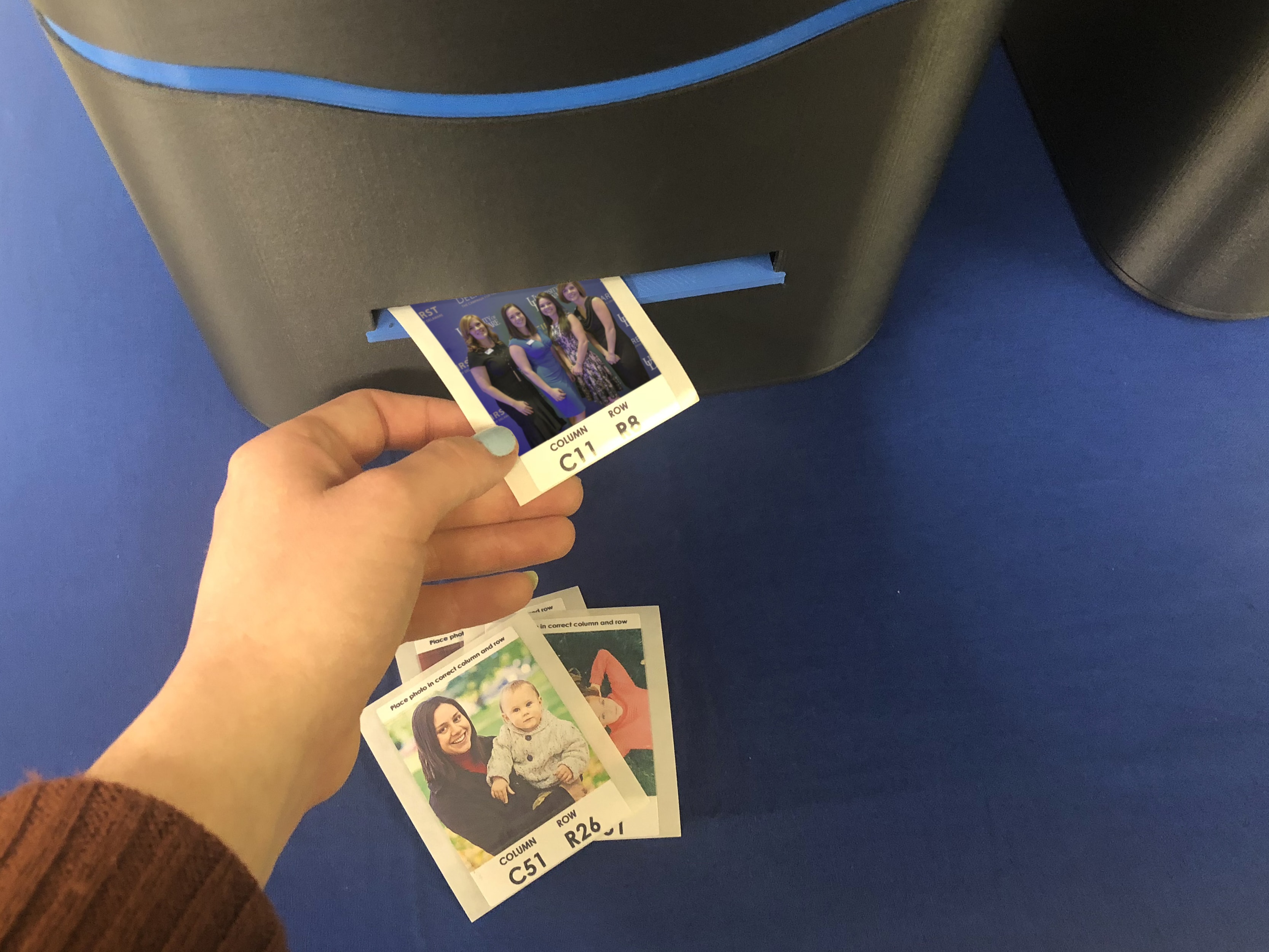 Guest retrieving printed photo tile from live mosaic printer for placement