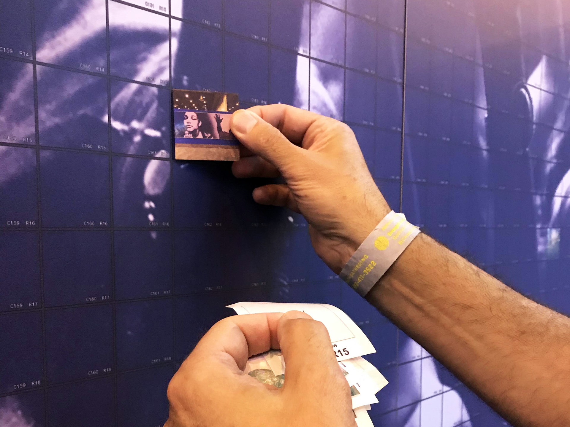 Close-up of a staff member applying a photo tile to the mosaic grid.