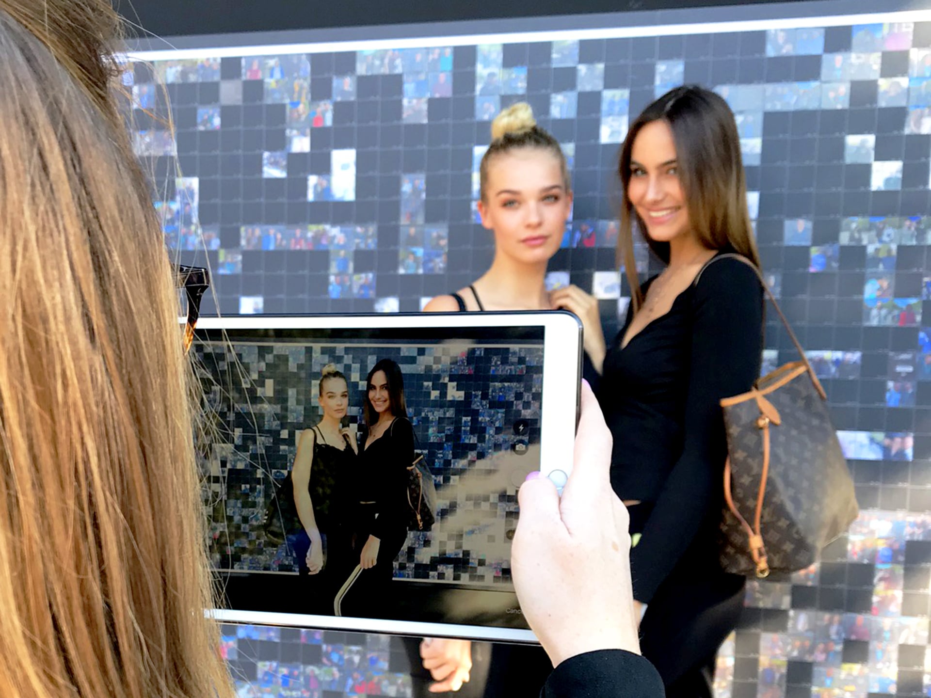 Models posing in front of the DJI mosaic wall during the Photokina event.