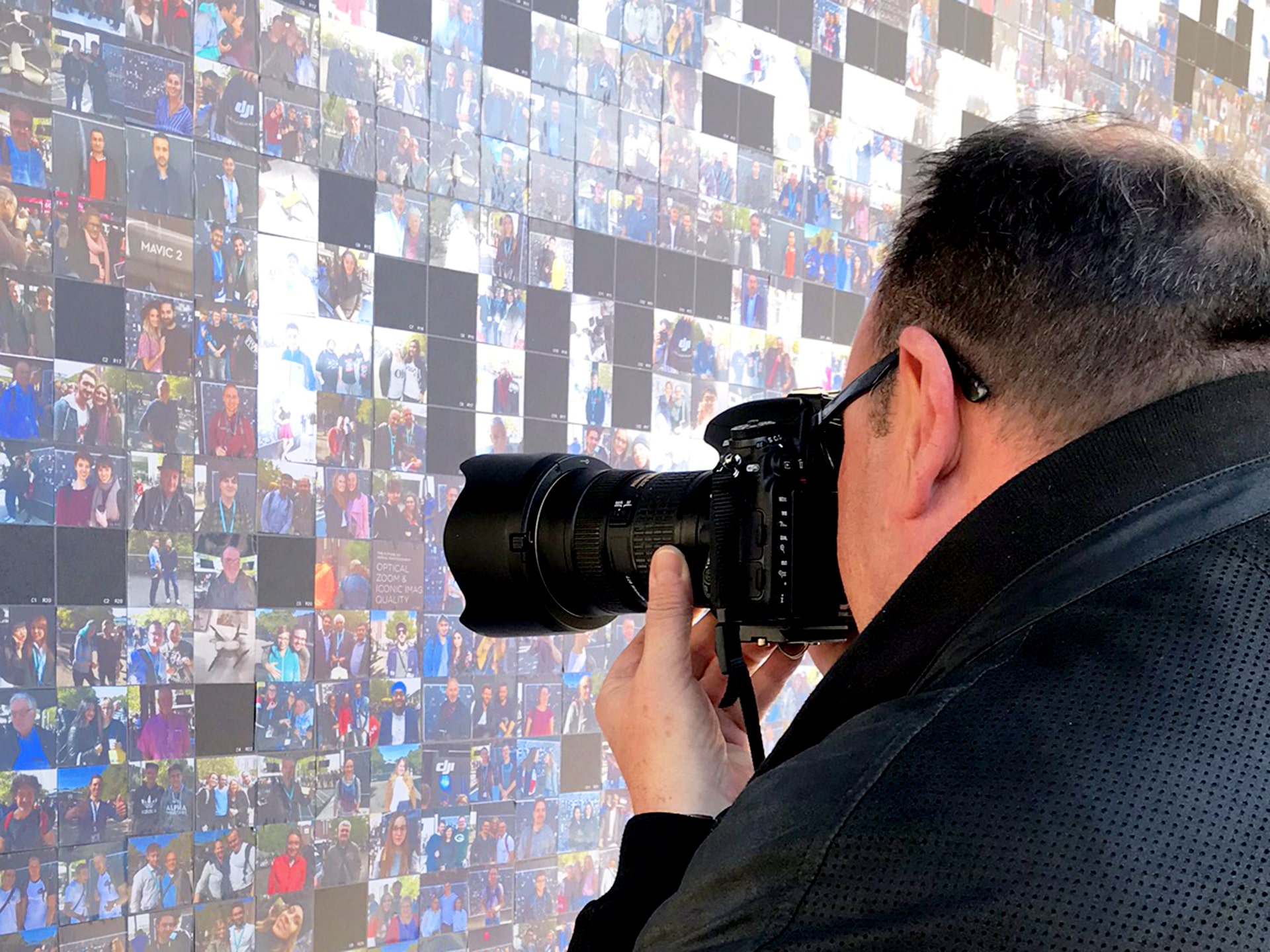 An attendee takes a photo of the evolving DJI mosaic wall at Photokina.