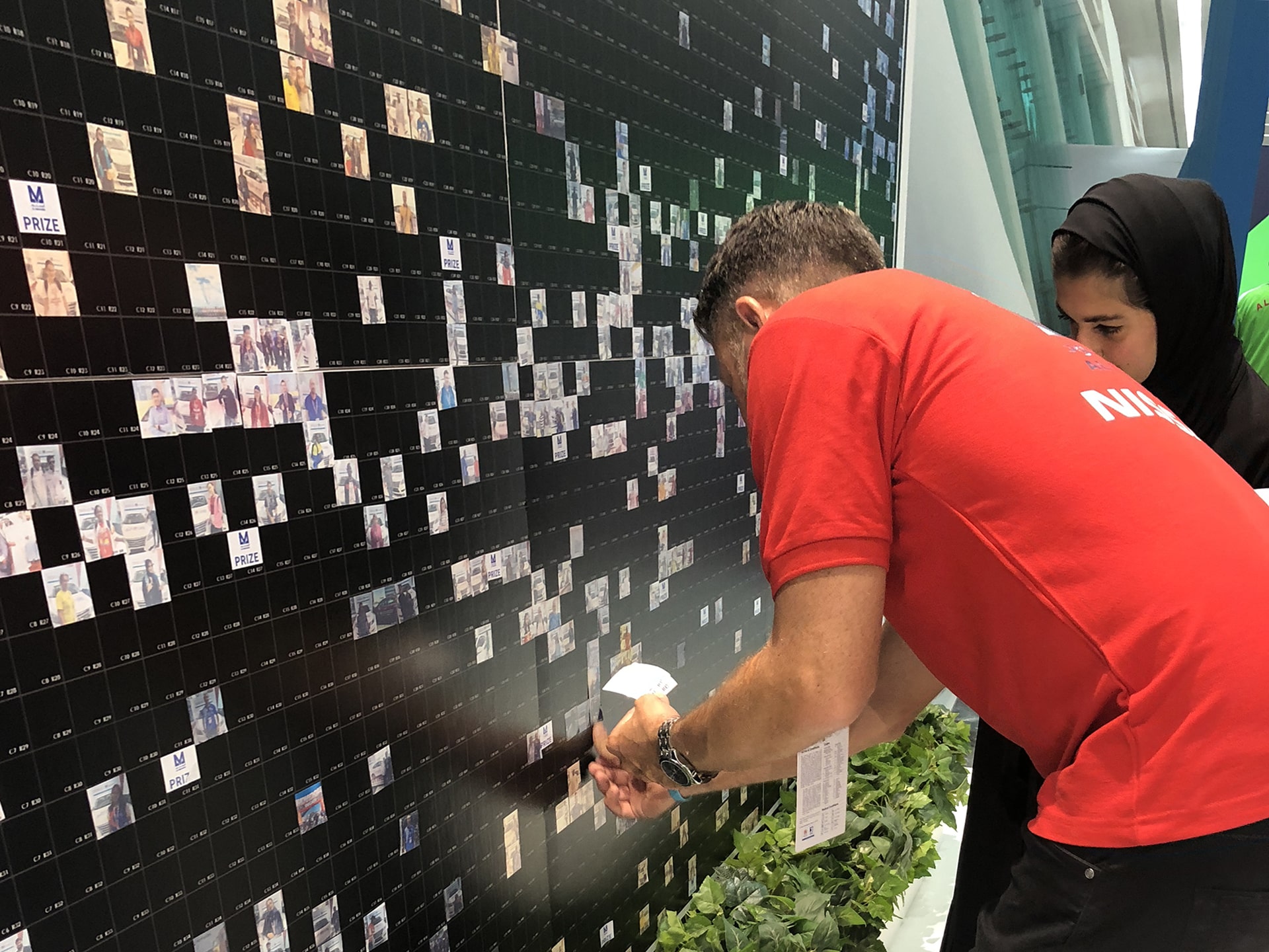 A volunteer assists an athlete in placing their image onto the mosaic wall at the 2019 Special Olympics World Games.