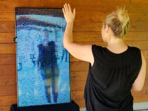 Woman standing in front of a vertical TV screen, watching as a Mirror Mosaic updates in real-time as she dances