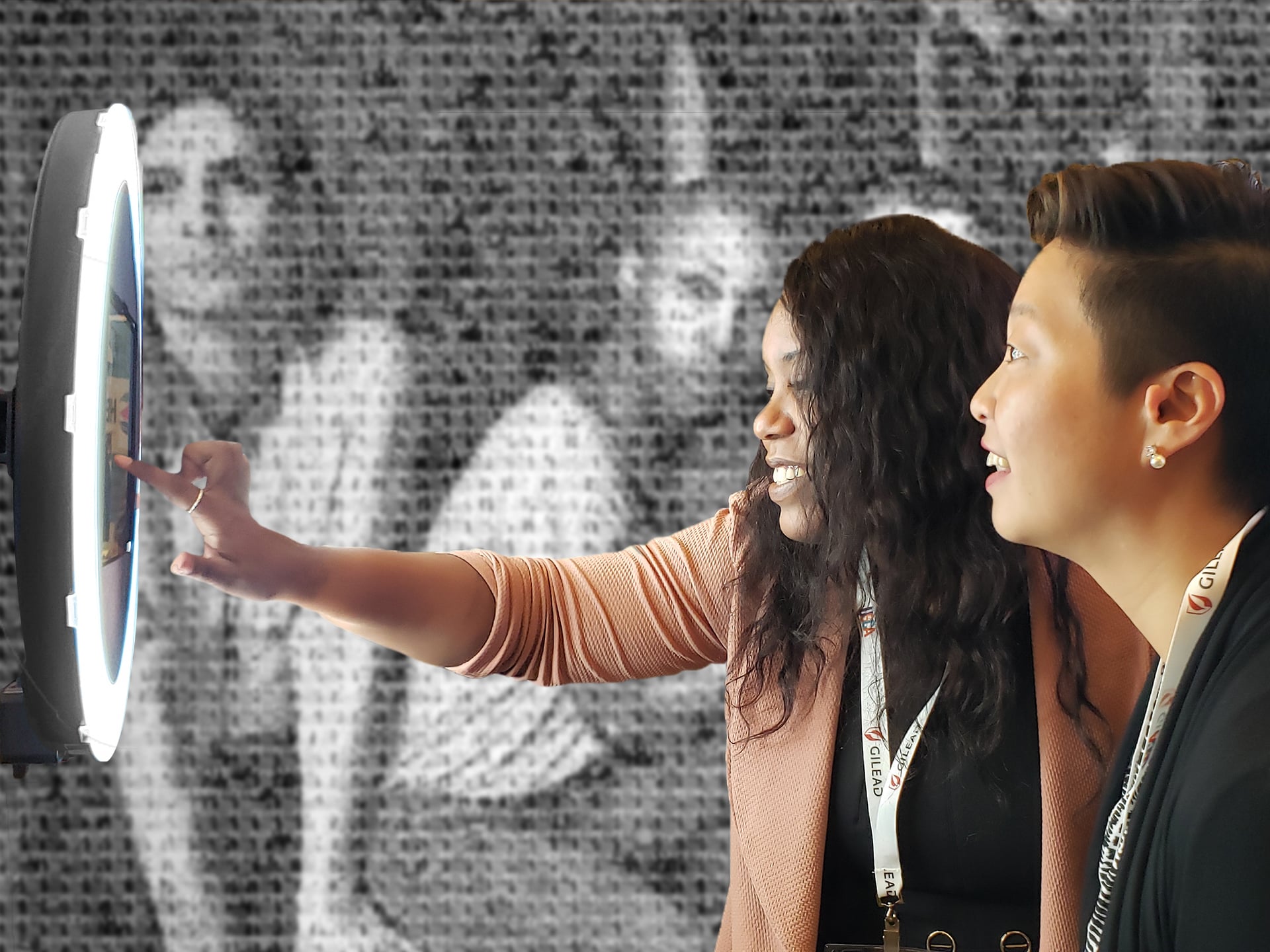 Two guests posing in front of the mosaic to receive their personalized photo tile