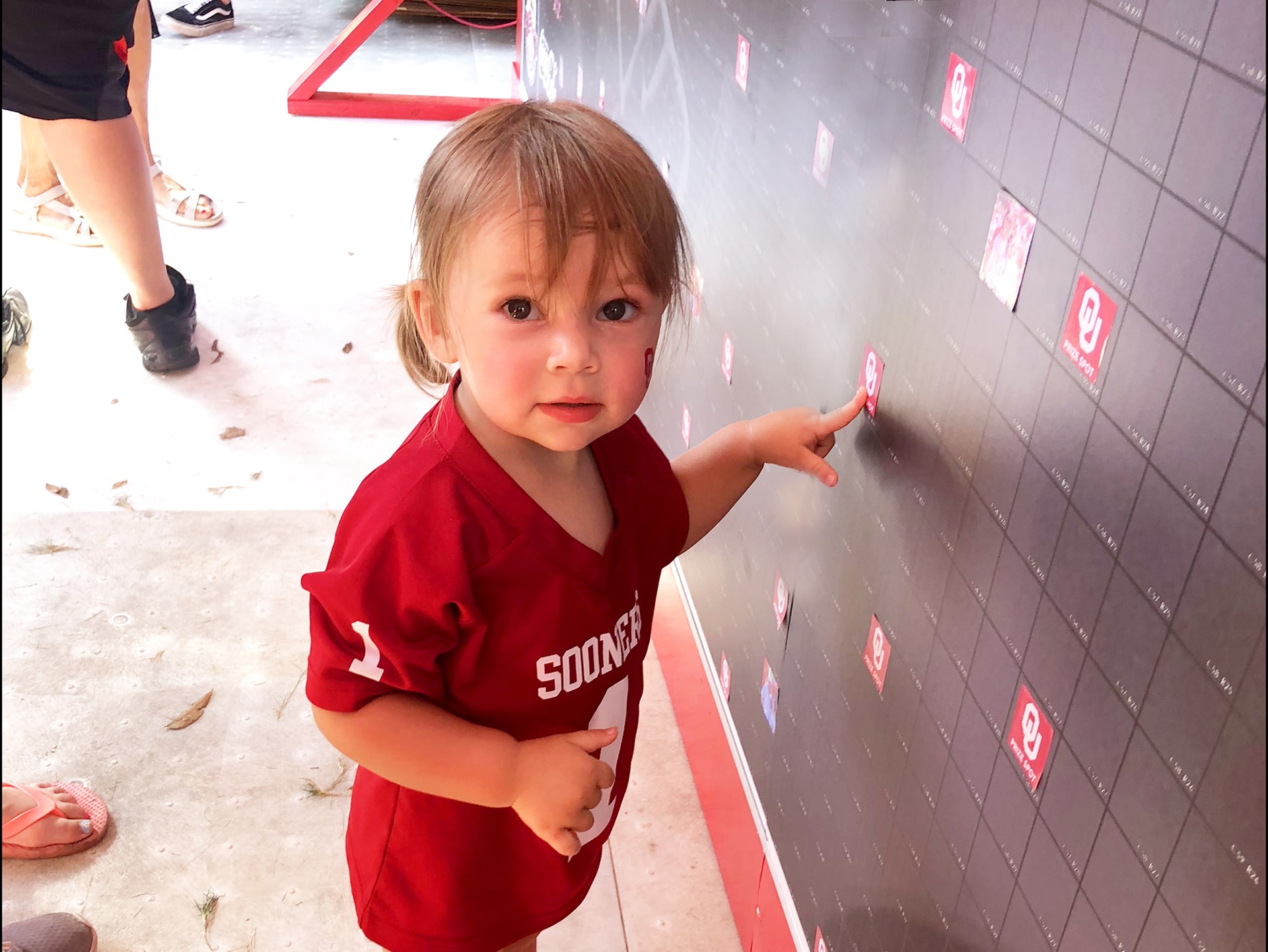 Child pointing at a prize tile within the completed photo mosaic display