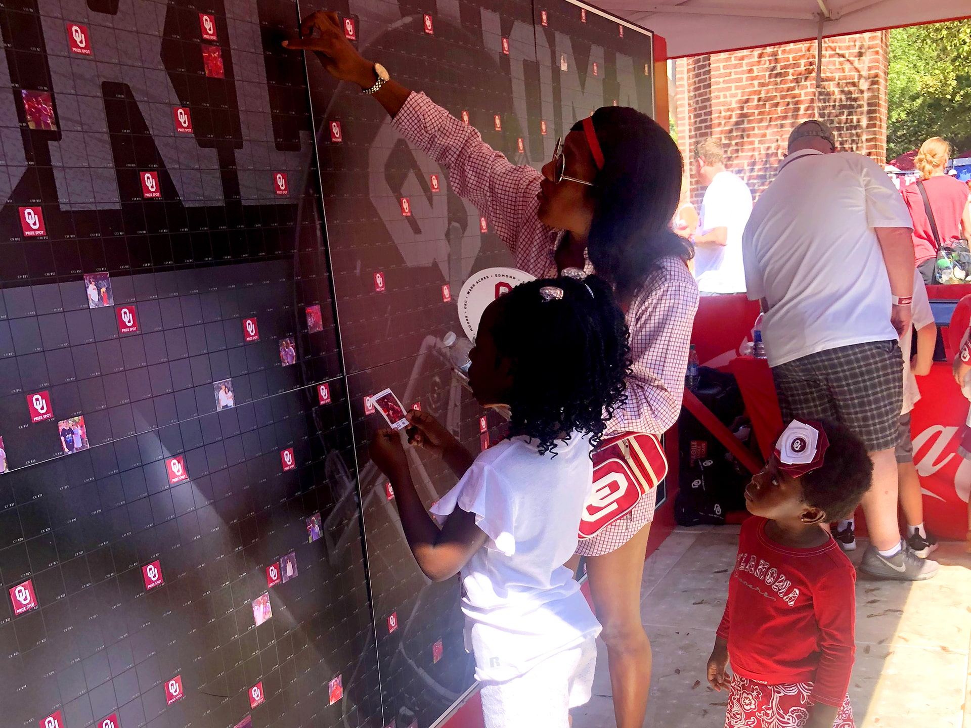 Mother and two children placing their photo tile onto the Coca-Cola mosaic