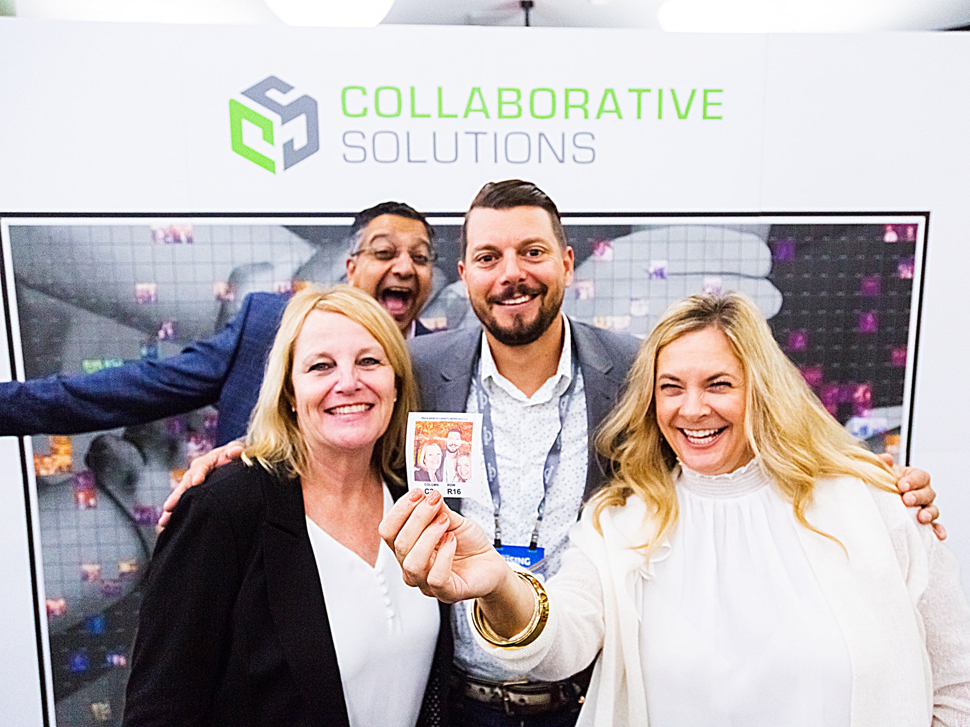 Group of attendees posing with their photo tile in front of the mosaic display