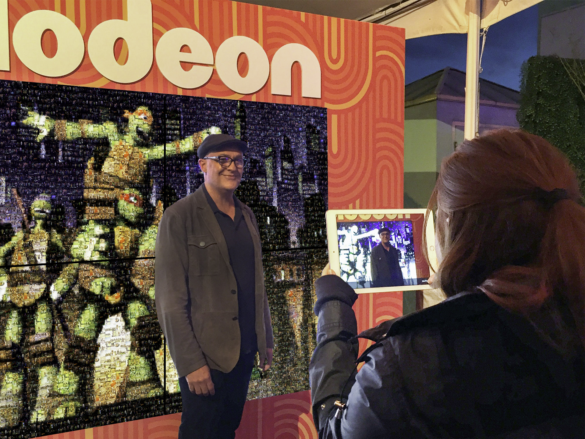 Brand ambassador taking a photo of a guest in front of the Live Digital photo mosaic