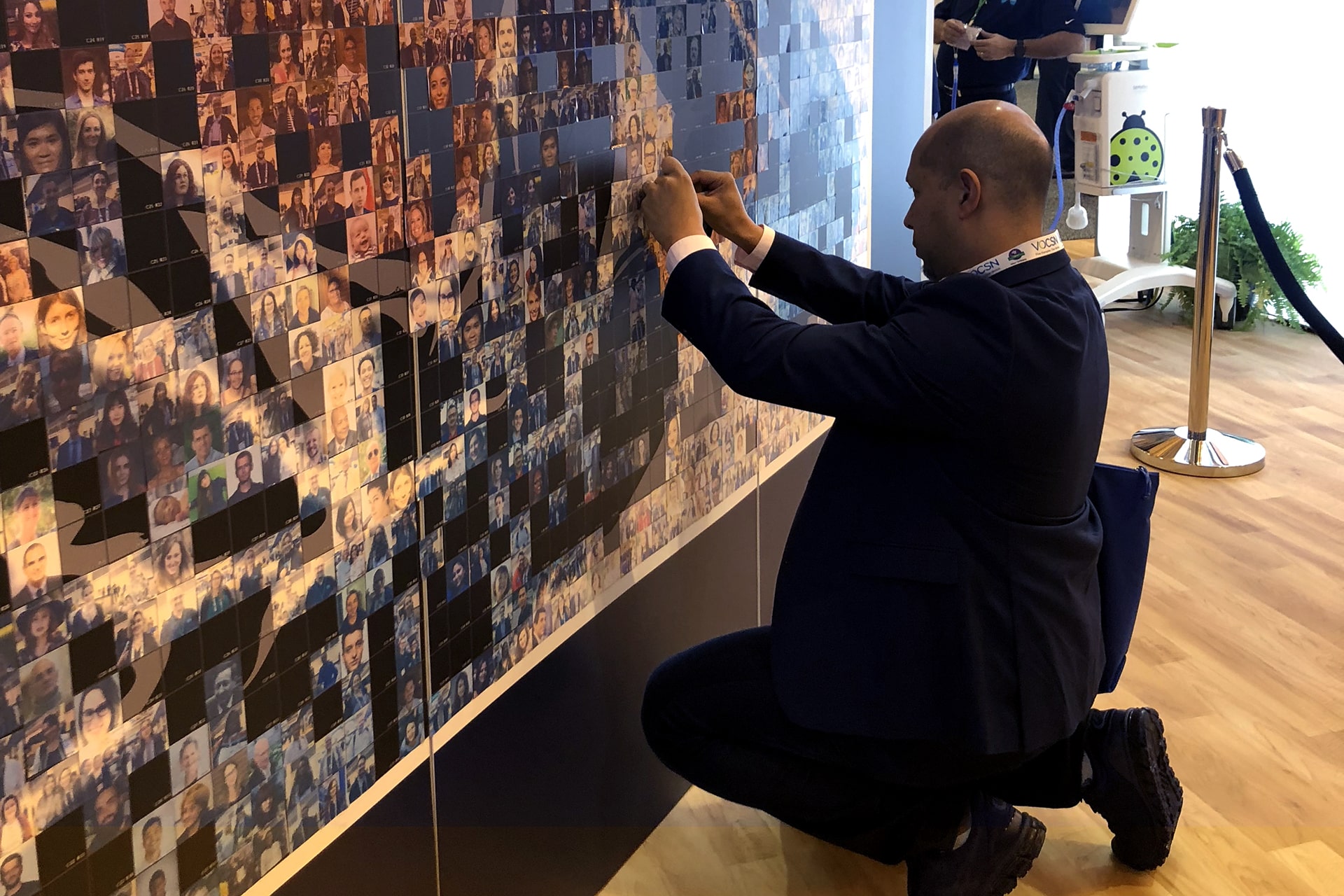 A participant placing their photo on the Live Print Mosaic wall at the AARC 2019 event