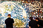 Three attendees simultaneously placing photo tiles on the mosaic wall