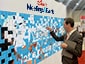 Man placing an adhesive portrait onto a Live Sketch Mosaic wall for Disney Meetings & Events