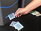 Close-up of a person taking a custom printed sketch from a printer, with other sketches scattered on the table