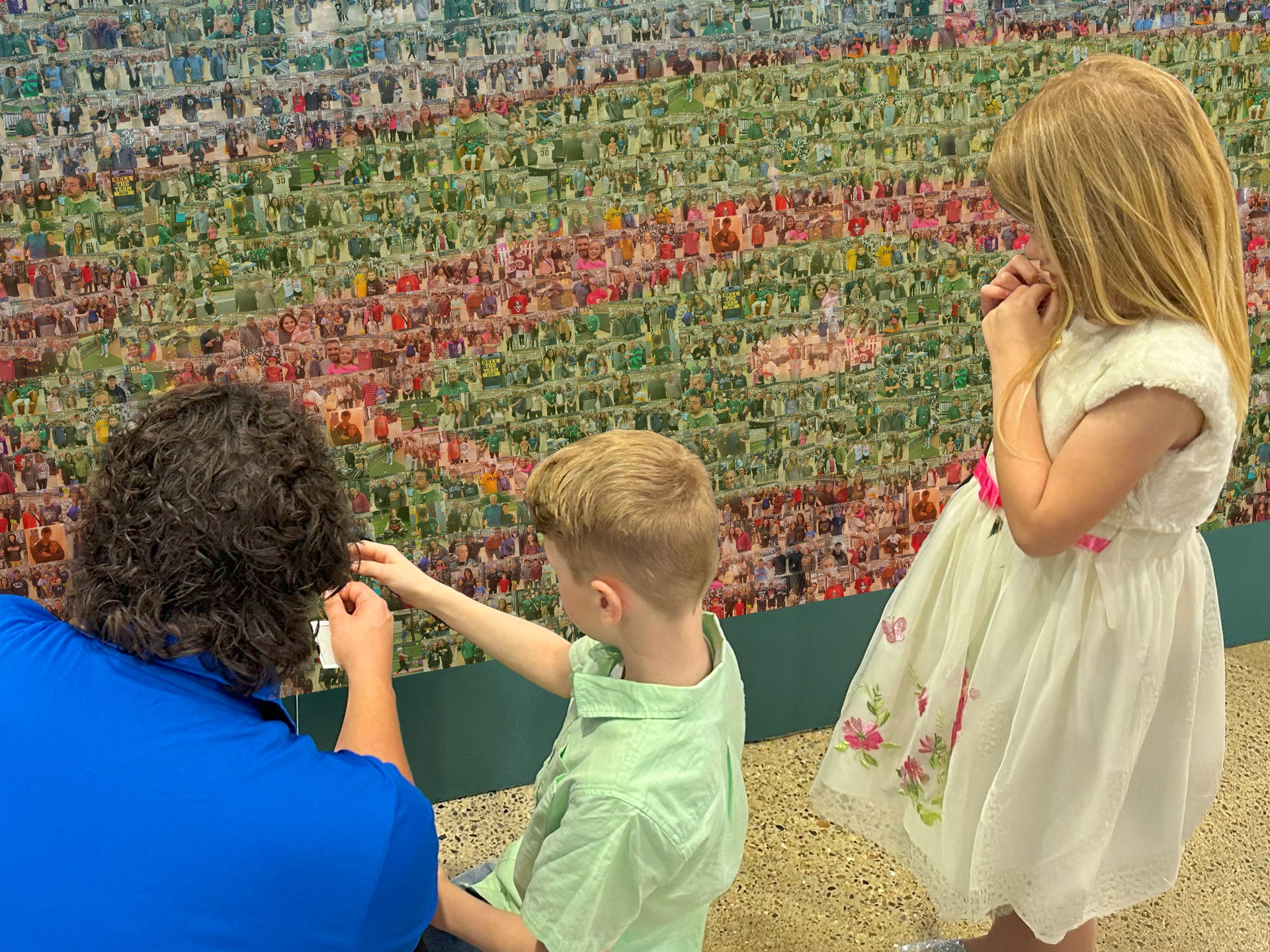The event tech helping two children add their photo into the mosaic in order to complete it