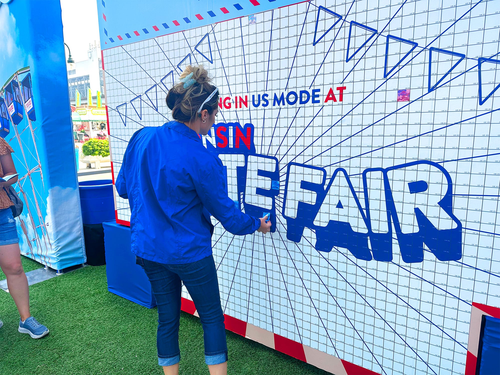 A guest placing their photo onto the photo wall at the Wisconsin State Fair