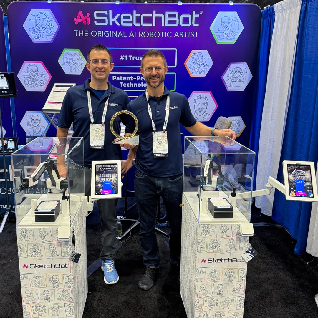 The founders standing behind the SketchBots Kiosks with the Brass ring award