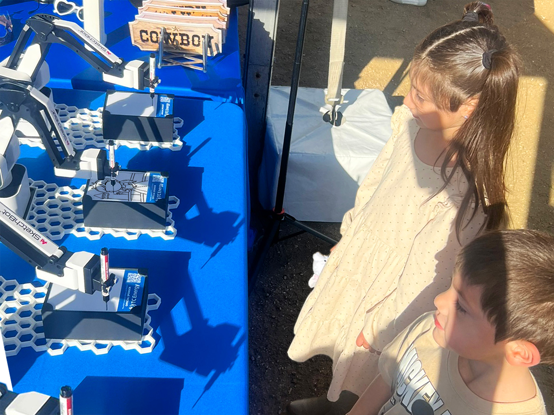 Two children watching their sketch be drawn by the SketchBots