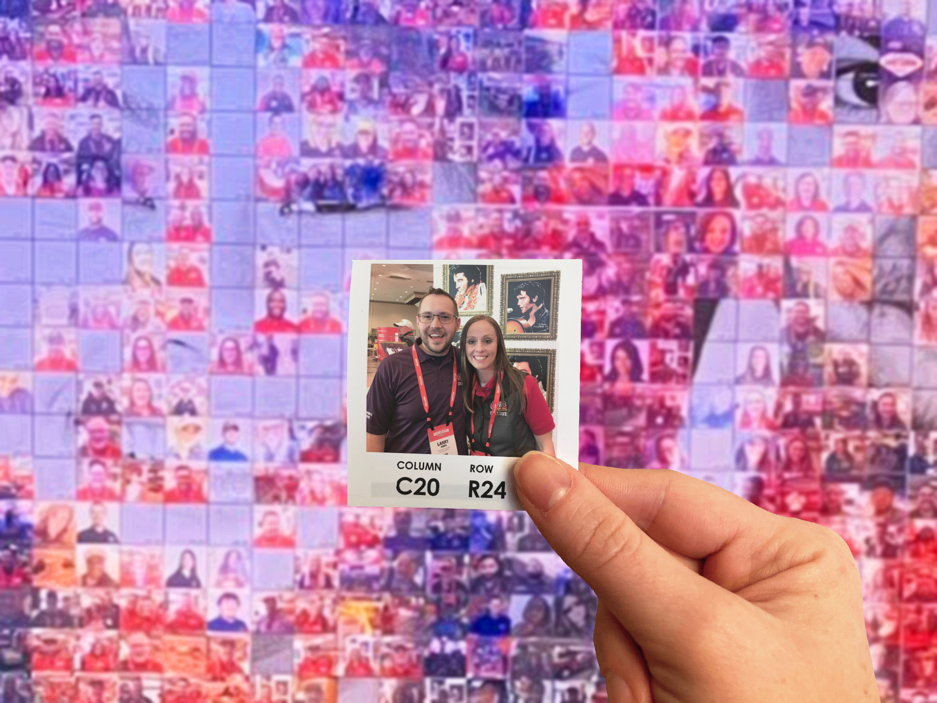 A guest holding their photo up in front of the photo mosaic wall