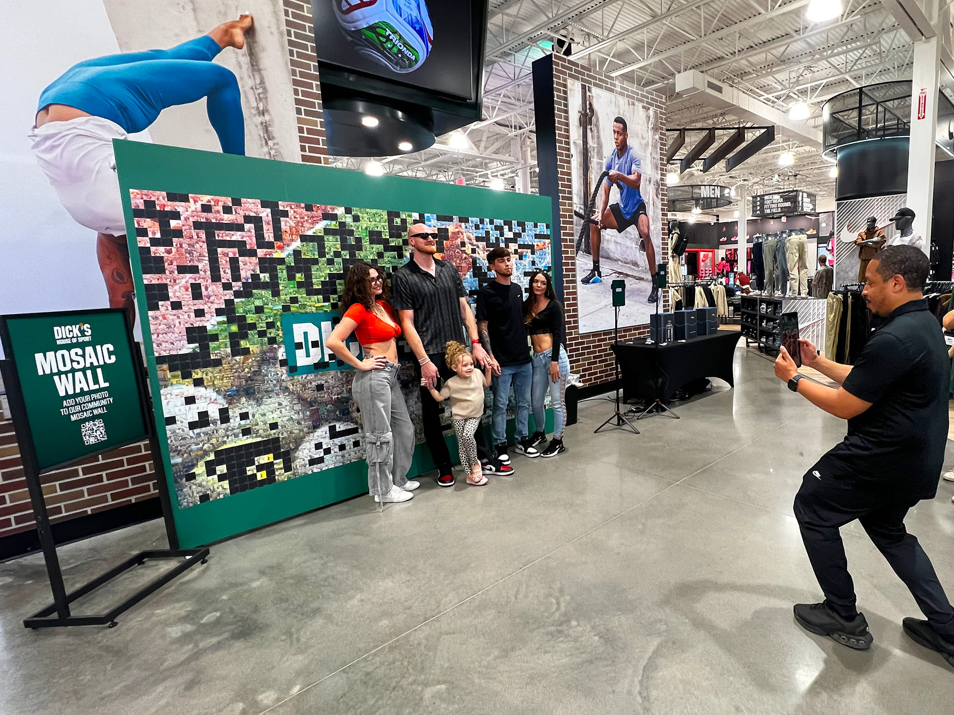 A photographer taking a photo of a group of people in front of the mosaic