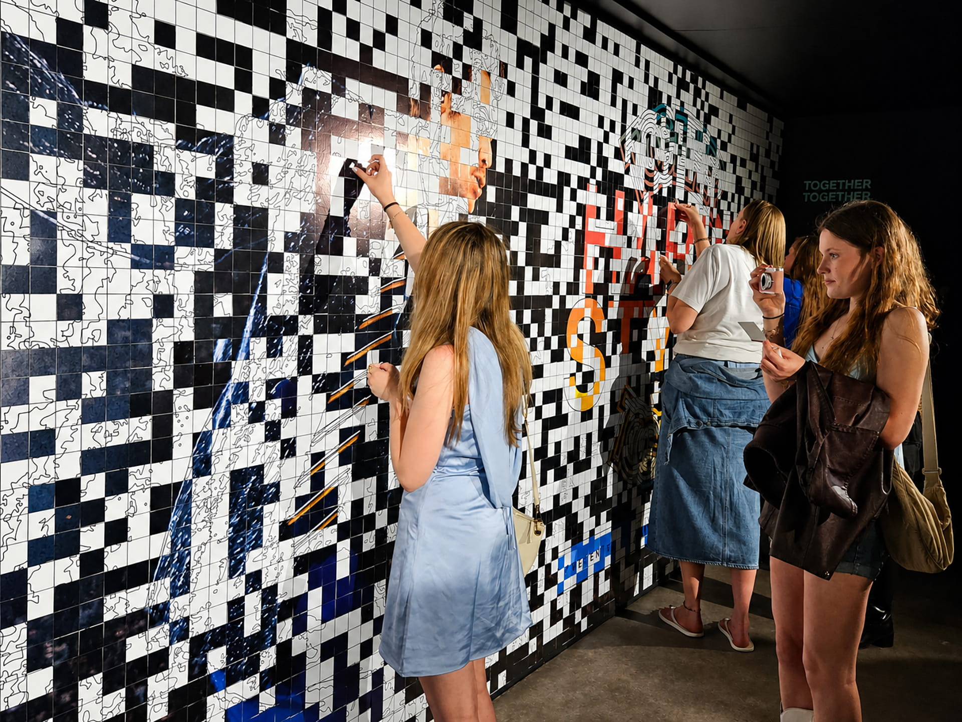 A girl adding a sticker to the large Harry Styles mosaic