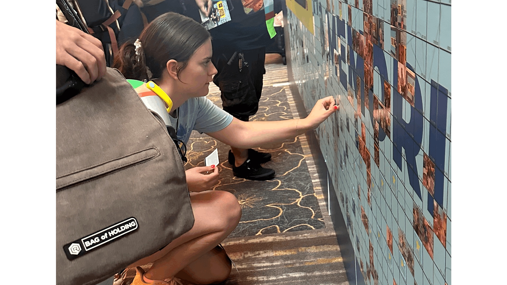A woman placing her photo on the mosaic wall