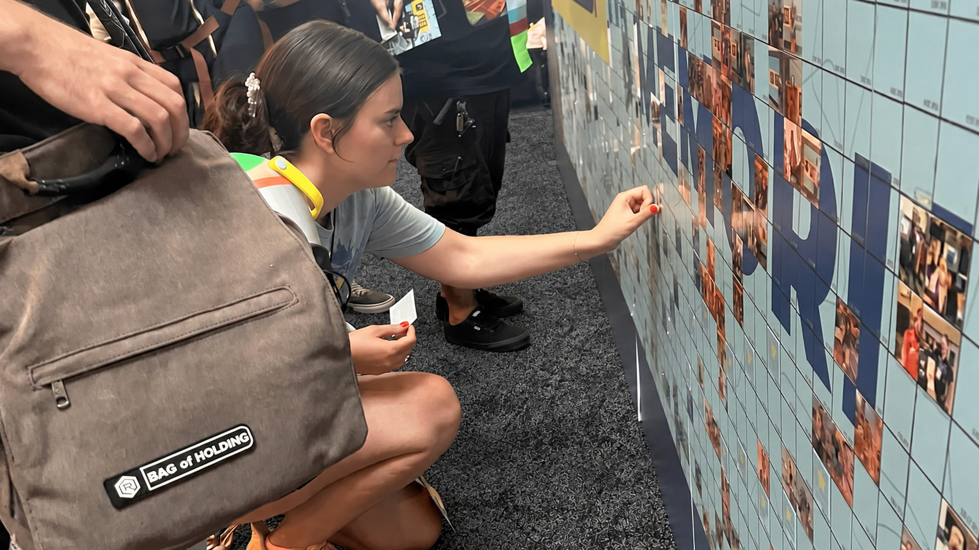 A woman placing her photo on the mosaic wall