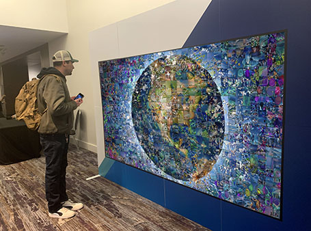Man looking ta the physical Earth Ai photo mosaic wall at an event