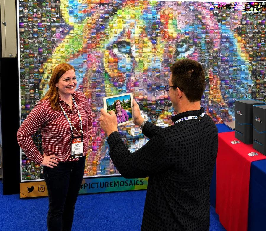 Guests posing in front of a live print mosaic wall while a tablet captures their photo.