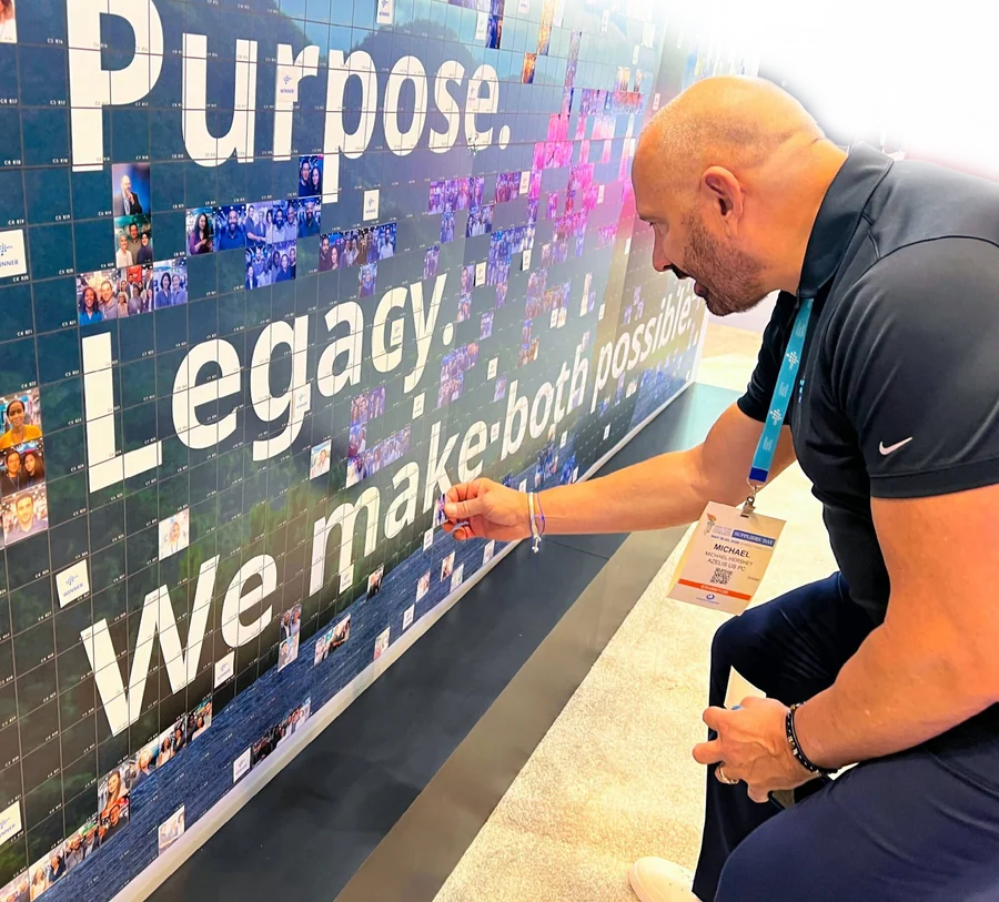 Guest placing a cell on a mosaic wall with a phone sharing the experience.