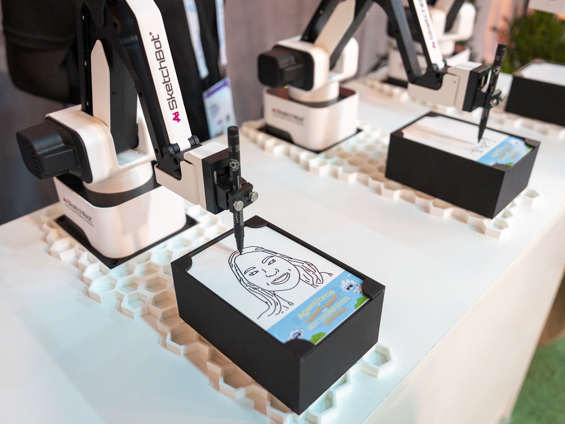 Zeichnungsroboter, der bei einer Veranstaltung ein detailliertes Porträt auf Papier skizziert, während die Teilnehmer im Hintergrund zusehen