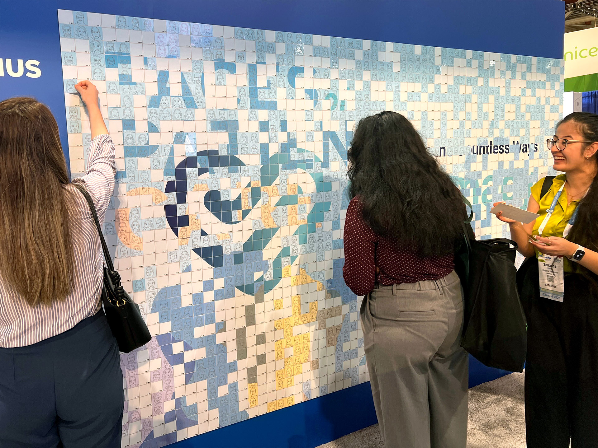Konferenzteilnehmer auf der Suche nach dem Platz ihres Porträts in einer Ai SketchBot-Mosaikwand