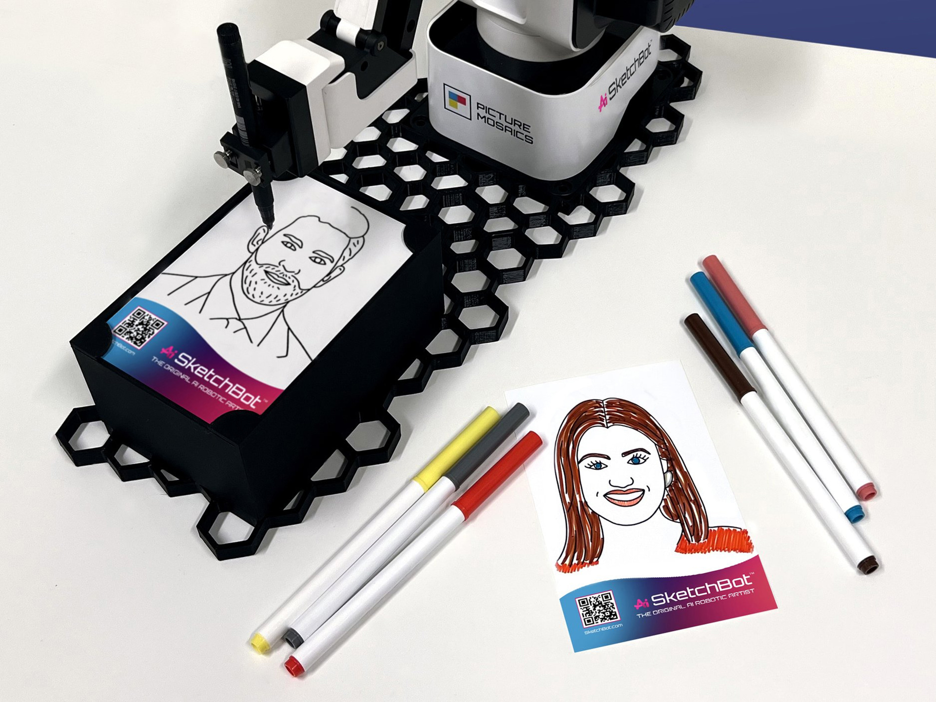 Ai SketchBot umgeben von Markern und Porträtskizzen, handkoloriert von Gästen